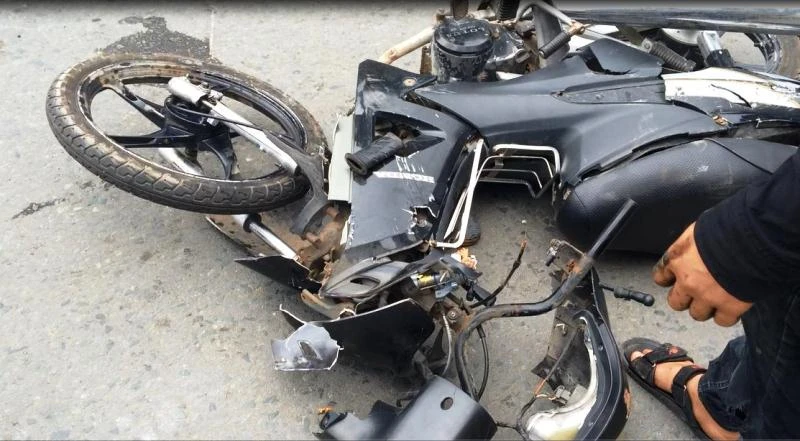 Chiếc xe máy bị mắc kẹt dưới gầm xe tải sau va chạm, hư hỏng nặng 